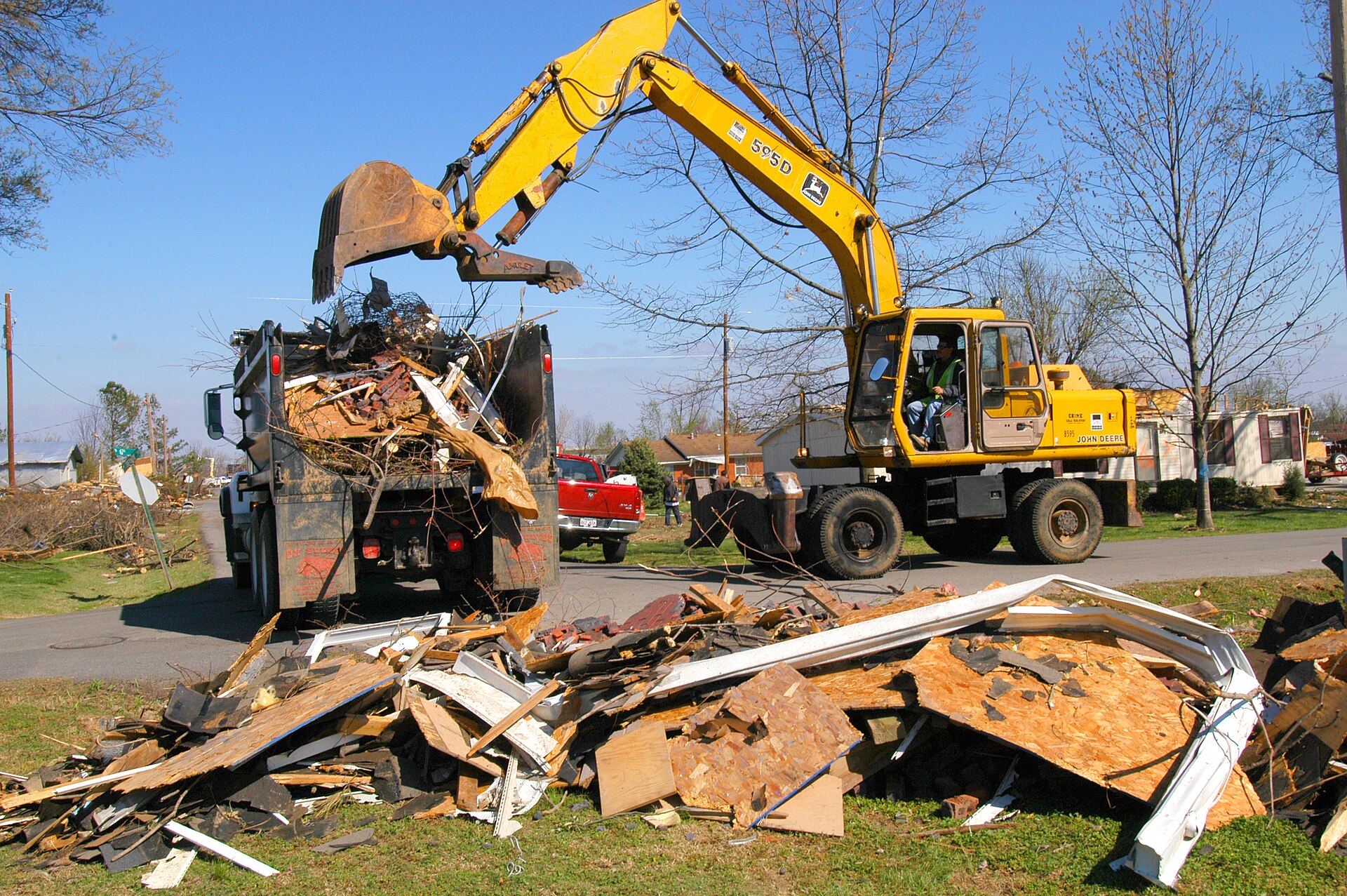 Excavator loading storm debris into a dump truck