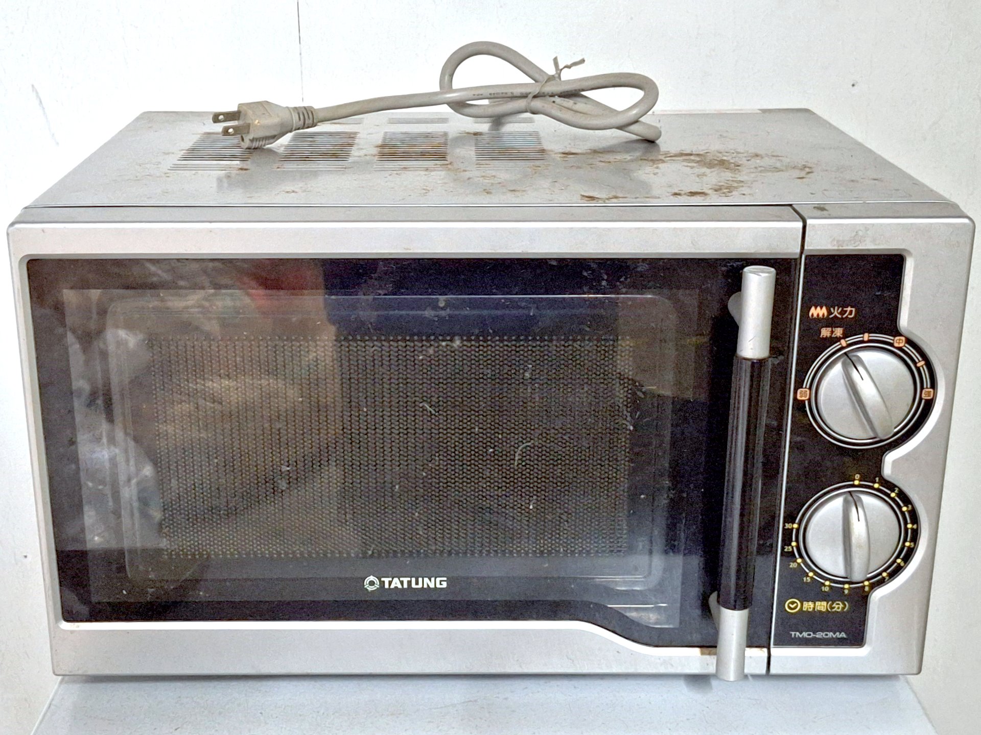 Front of an abandoned countertop microwave oven left in a basement