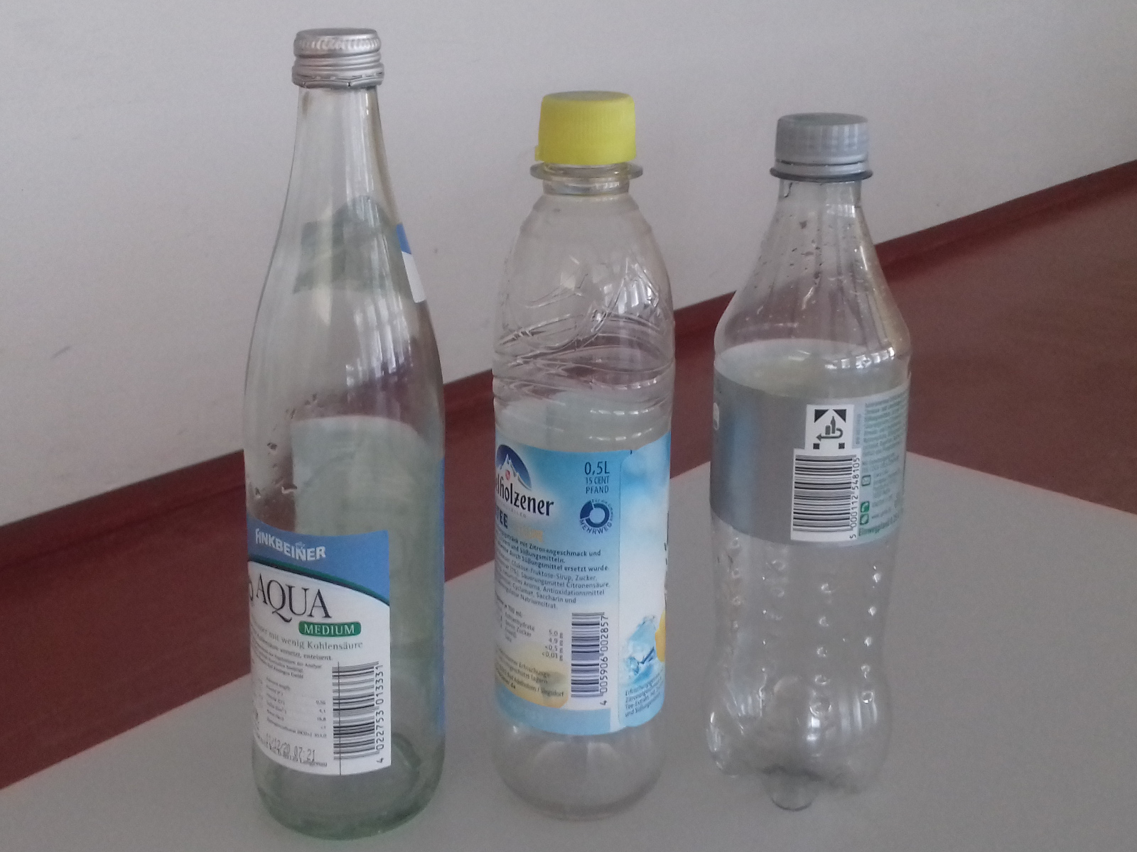 Three reusable and single-use beverage bottles standing side by side