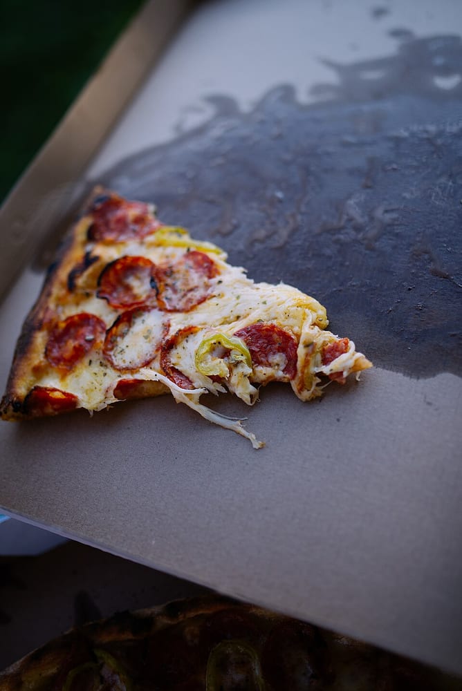 A slice of pizza in a cardboard pizza box