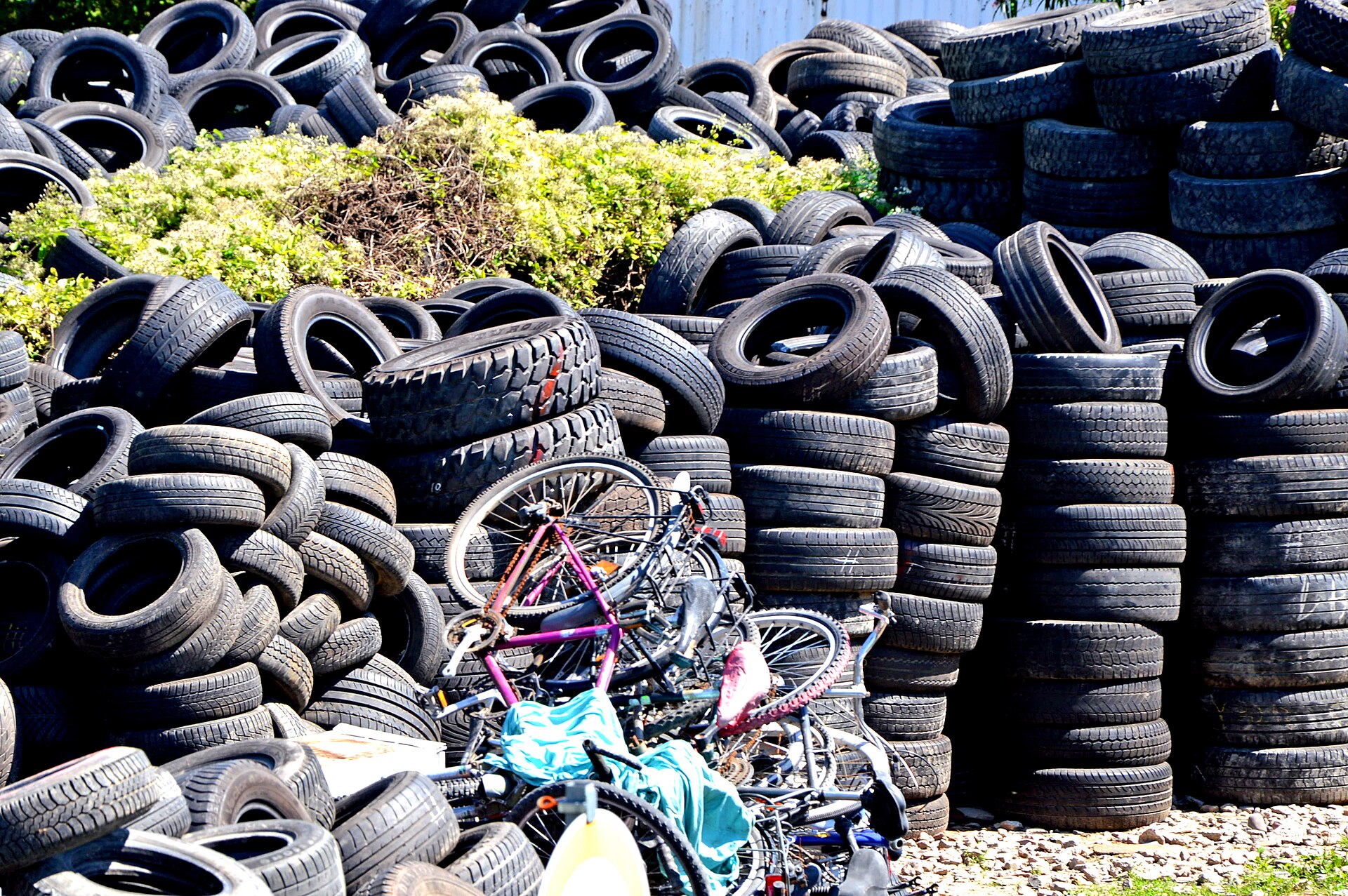 Stacks of used car tires waiting to be hauled away for recycling in an industrial area of Wesseling, Germany, with discarded bicycles in front